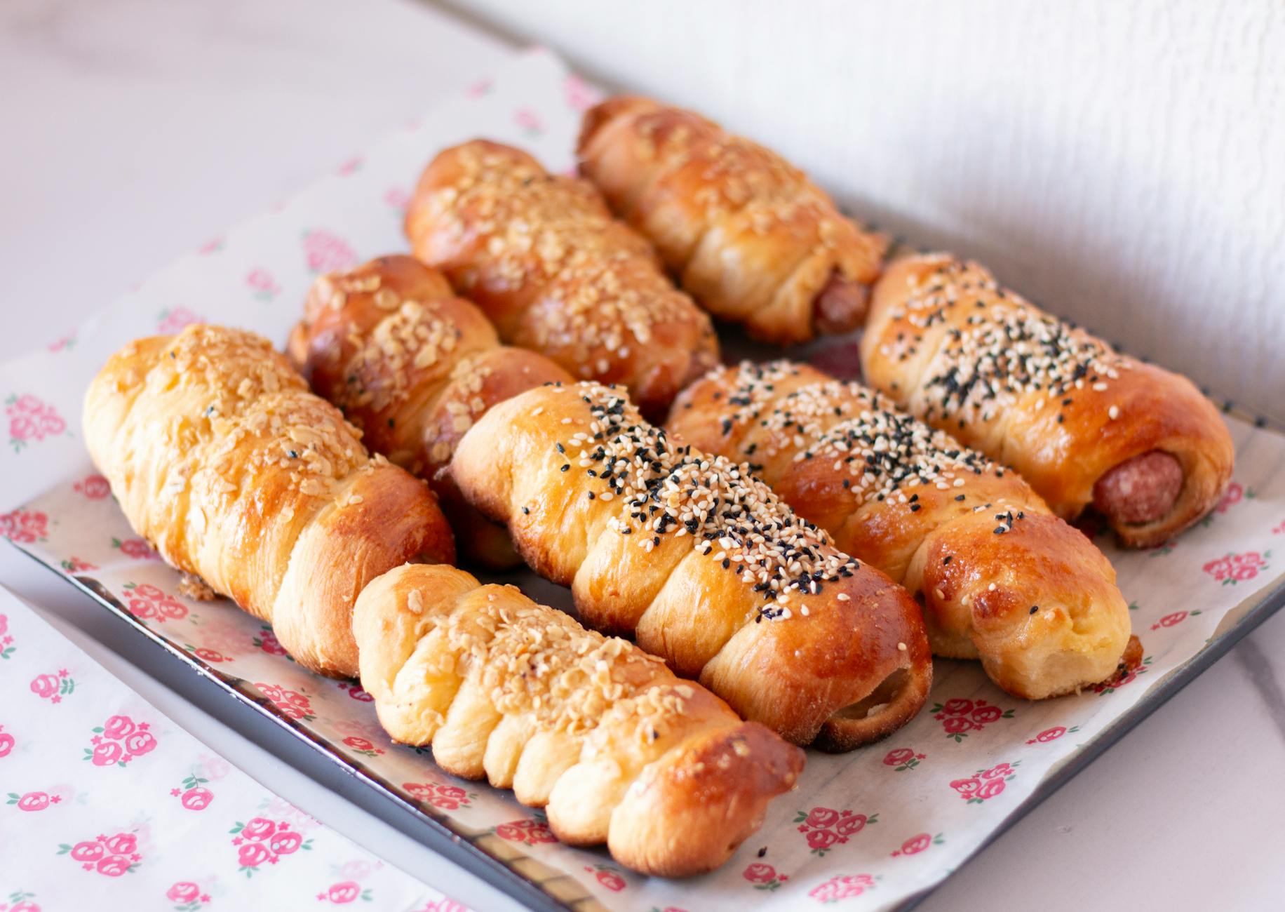freshly baked sausage rolls with sesame toppings